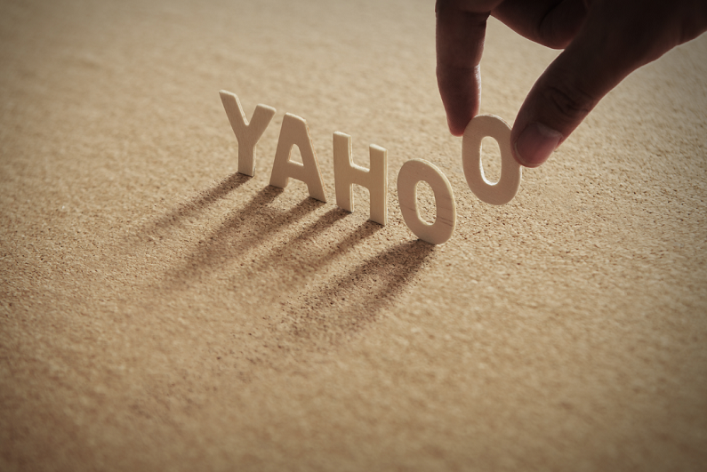 Person lifting letter 'O' from word 'YAHOO' made from wood