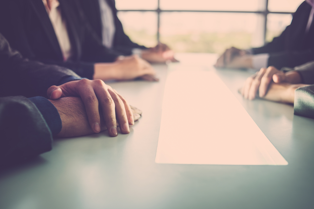 businesspeople in suits sitting around a board room table