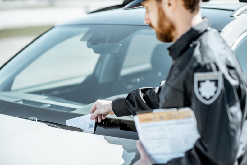 Police officer placing a ticket on a car windshield