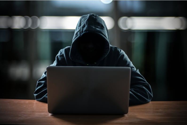 Hooded "hacker" using a laptop